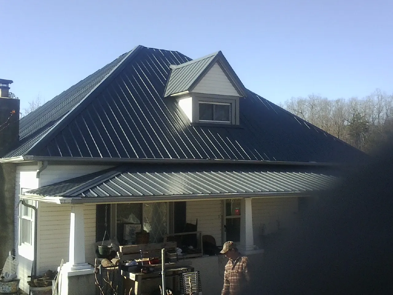 Dark blue standing seam metal roof with a dormer above a front porch in Bristol